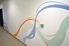 the wall is painted with colorful swirls in an office building corridor area that has tile flooring and white walls