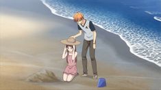 a man and woman standing on top of a sandy beach next to the ocean,