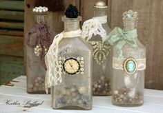 three glass bottles with lace and buttons on them