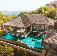 an aerial view of a house with a swimming pool in the foreground and two people lounging on the deck