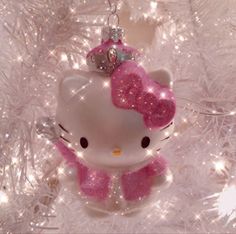 a hello kitty ornament hanging from a white christmas tree decorated with pink glitter