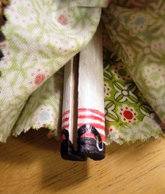 two wooden sticks sitting on top of a table next to a cloth covered wallpaper