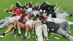 a group of people laying on top of a lush green field next to each other