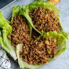 two lettuce wraps with meat and vegetables in them next to a tray of sliced ginger