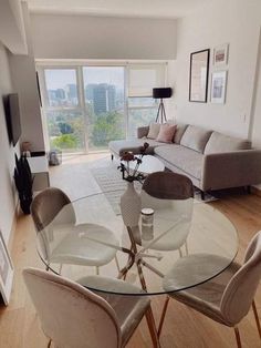 a living room filled with furniture and a glass top table in front of a large window