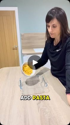 a woman sitting at a table with a bowl of macaroni and cheese