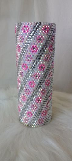 a white vase with pink and grey designs on it's sides sitting on a fur surface