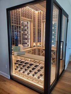 a wine cellar with lots of bottles in it's glass doors and lights on the walls