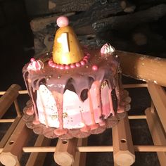 a pink and gold birthday cake sitting on top of a wooden rack