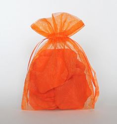 an orange organ bag filled with small pieces of fruit on top of a white surface