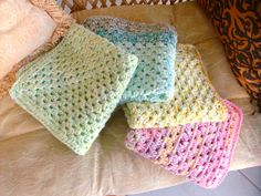 four crocheted blankets on top of a bed next to pillows and a pillow