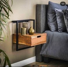 a bedroom with a bed, nightstand and plant on the side table next to it