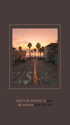 an empty parking lot with palm trees and the sun setting in the distance behind it