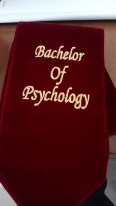 a red book with the words bachelor of psychology written on it sitting next to a laptop