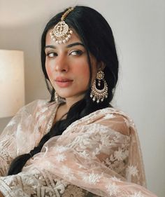 a woman in a sari sitting on a couch with her arms crossed and looking off to the side