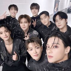 the group is posing for a photo in front of a white wall with black and silver decorations