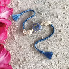 a blue and white beaded bracelet with an initial charm on it next to pink flowers