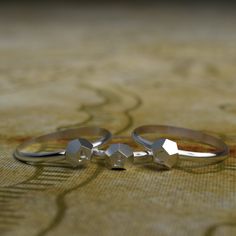 two silver rings sitting next to each other on top of a wooden tablecloth covered floor