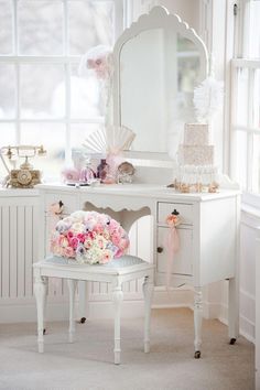 a white dressing table with flowers and a mirror