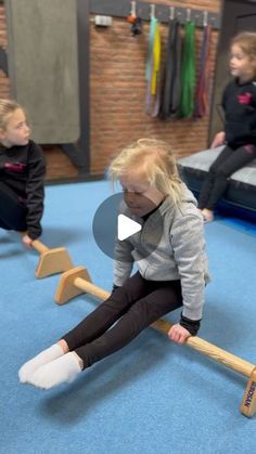 two young children playing on wooden seesaws in a play room with blue carpet