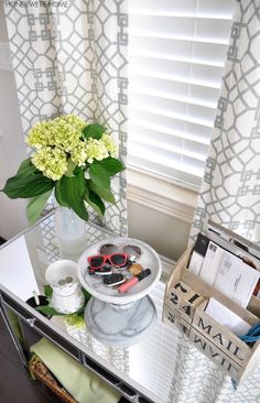 a table topped with a vase filled with flowers and crafting supplies next to a window