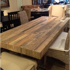 a large wooden table sitting in the middle of a room with wicker chairs around it