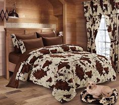 a cow print comforter set on a bed in a room with wood paneled walls