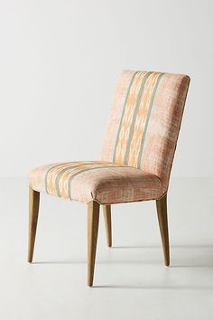 an upholstered chair with wooden legs and a striped fabric seat cover on the back