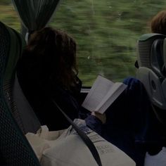 two people sitting on a bus looking out the window at grass and trees in the distance