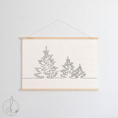 a drawing hanging on the wall next to a white wall with a wooden frame that has trees drawn on it