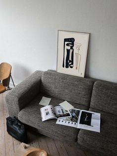 a grey couch sitting on top of a hard wood floor next to a wooden chair