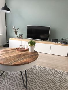 a living room with a large tv on top of a wooden table in front of a white entertainment center