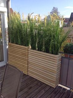 a wooden planter sitting on top of a wooden deck next to a patio table