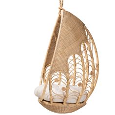 a wicker hanging chair with white pillows in the shape of a sailboat on it