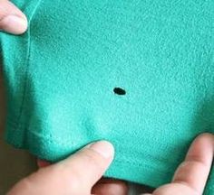 someone is removing the black spot from their green t - shirt