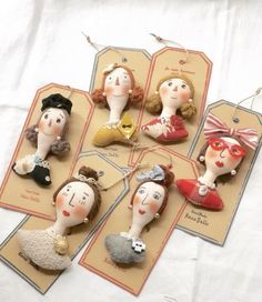 six little dolls are hanging from tags on the table