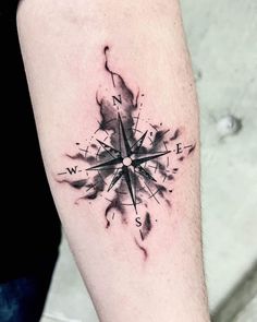 a black and white compass tattoo on the arm