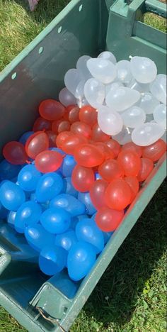 there are many balloons in the bin on the grass