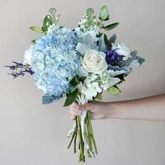 a person holding a bouquet of blue and white flowers