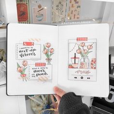 a hand holding an open notebook with some drawings on the pages and flowers in vases