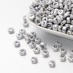 a bowl full of metal letters sitting on top of a white table next to blue and green squares