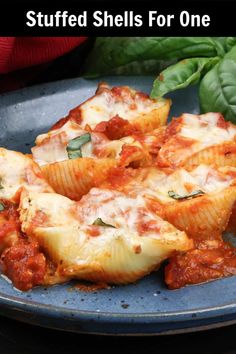 stuffed shells for one on a plate with spinach leaves and basil in the background