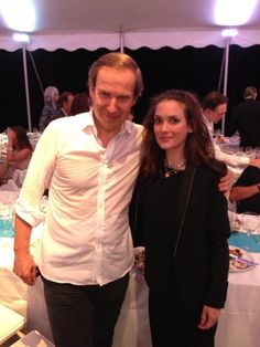 a man and woman standing next to each other in front of a table with food on it