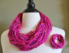 The beautiful arm knit scarf and crochet bracelet are made with 100% wool and shimmering ribbon yarn in fuchsia. The variety of yarn give this necklace and bracelet a great texture. This scarf is the perfect cozy accessory for cold weather! Wear with an oversize sweater, skinny jeans, and ankle booties. This scarf is a double loop for those that want a bit of bulk and will add a great pop of color to any outfit. The necklace is arm knit and the bracelet is crocheted for a tighter look. The brace Arm Knit Scarf, Bracelet Au Crochet, Arm Knitting Scarf, Knit Necklace, Ruana Wrap, Arm Knit, Beautiful Arms, Bracelet Crochet, Knitted Necklace