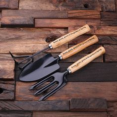 three garden utensils with wooden handles on top of a wood floor next to each other