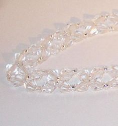 a white beaded bracelet with clear beads on a white tablecloth, close up