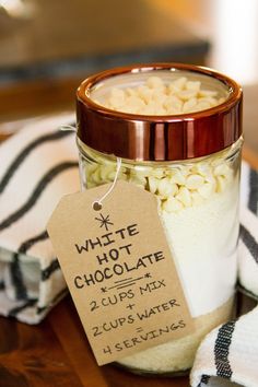 a glass jar filled with white chocolate chips next to a striped towel and a tag