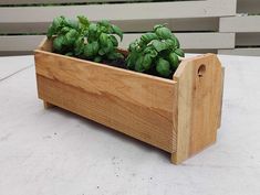 a wooden planter filled with green plants on top of a table