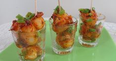 three glasses filled with food sitting on top of a green tray next to each other