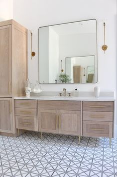 a bathroom with a sink, mirror and cabinets on the wall next to each other